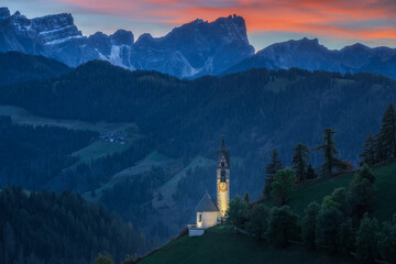 Fototapeta na wymiar Small church in the mountain at sunset and night, Chiesa di Santa Barbara in Dolomite Alps, Italy