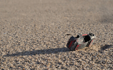 Aged miniature car simulating a road accident, sand, overturned