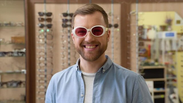 Young man choosing retro oval sunglasses