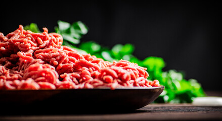 Minced meat on a plate on the table with parsley.  - obrazy, fototapety, plakaty