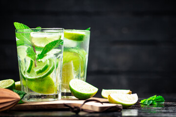 Mojito with pieces of lime on a cutting board.