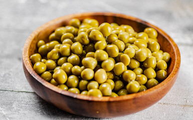 Full wooden plate with canned green peas.