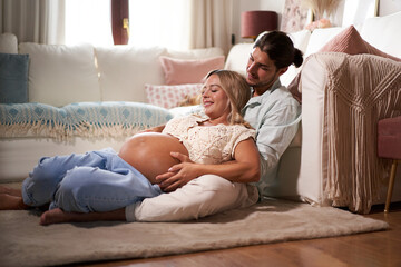 Pregnancy belly. Caucasian husband and pregnant wife hugging sitting at home. Family couple...