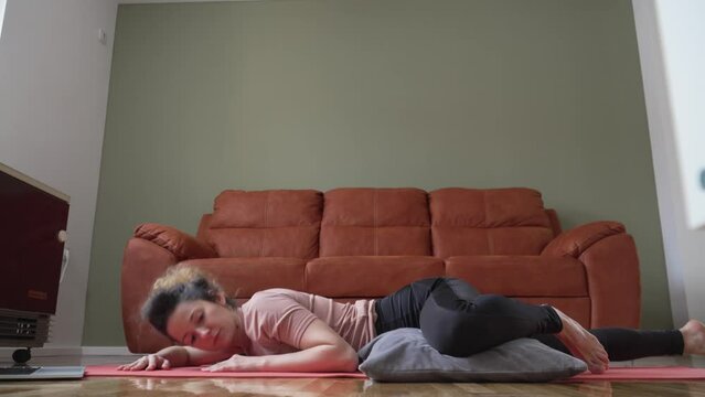 Adult caucasian woman practice restorative yoga on the floor at home