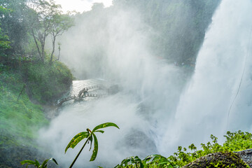 A water fall cascading through a jungle canyon with clouds of mist and spray, Dambri Falls, Vietnam