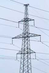 New large mast of an air power line close up, high voltage electricity pylon with thick wires and insulators, blue sky on background. Traditional energy. Electric power concept.