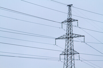 New large mast of an air power line close up, high voltage electricity pylon with thick wires and insulators, blue sky on background. Traditional energy. Electric power concept.
