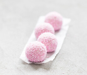 Obraz na płótnie Canvas Strawberry mousse cream balls, sprinkled with coconut shavings. On paper. Light background
