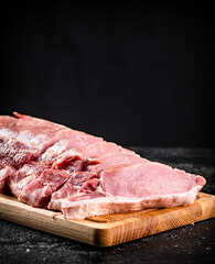 Raw pork sliced on a wooden cutting board. 