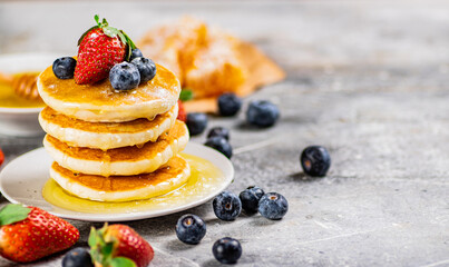 Pancakes with honey and berries on a plate.