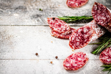 Pieces of salami sausage with sprigs of rosemary. 