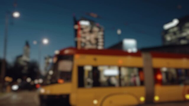 Blurred urban city landscape background, traffic jam city roadway, yellow trams and cars driving crossroad slow motion in evening. Downtown roadway cityscape, rush hour after work, car lights bokeh