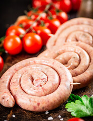 Round raw sausages with tomatoes and parsley. 