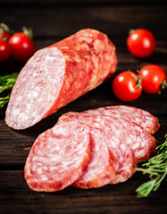 Pieces of delicious salami sausage with rosemary and tomatoes. 
