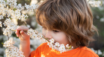 Close up portrait of cute child outdoors. Spring banner for website header. Spring boy in blooming park. Cute kid outdoor. Blooming tree in garden.