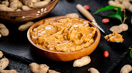 Peanut butter on a stone board with peanuts in the shell. 