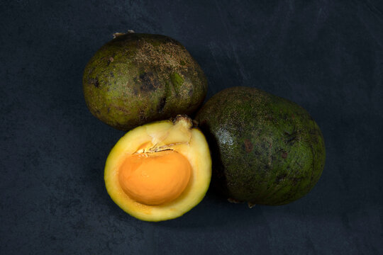 Portion of Brazilian fruit Pequi, or souari nut, whole and sliced on black background