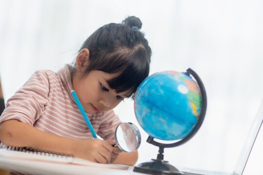 Asian little girl is learning the globe model, concept of save the world and learn through play activity for kid education at home.