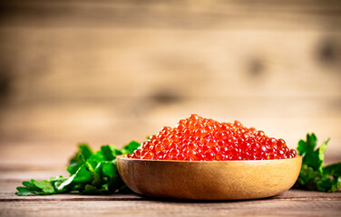 Red caviar in a plate on the table with parsley. 