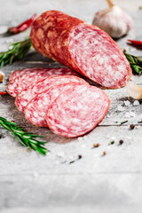 Pieces of salami sausage with spices, rosemary and chili peppers. 
