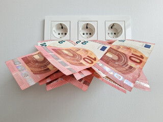 Increased electricity cost concept with money and AC socket