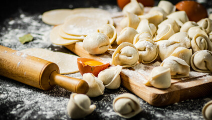 Raw dumplings with eggs, rolling pin and flour on the table. 