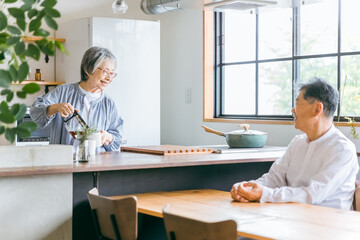 家のキッチンでコーヒーをいれる高齢者女性と高齢者男性（老夫婦）
