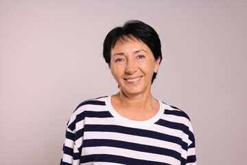 Portrait of smiling senior woman on light grey background