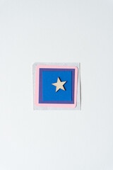 wood star on a set of paper squares in blue, purple, pink, and textured stone white