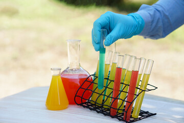 Closeup student hand wears blue glove, doing science experiment, lab lesson, holds test tube. Concept, science subject, project work. Experiment, education, learning by doing approach.  