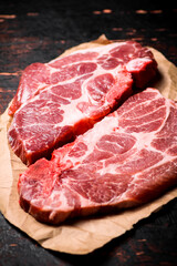 Raw pork steak on paper on the table. 