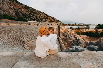 Fototapeta premium Happy lover couple tourist archaeologist in hat background old tomb Myra Ancient City in Demre to Antalya, archaeology of Turkey