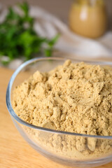 Bowl of aromatic mustard powder on table, closeup