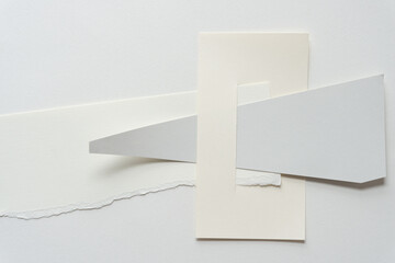 mostly gray and ivory abstract paper shapes (some geometric) on blank paper