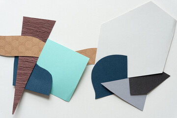 mostly brown, blue, and gray abstract paper shapes (some geometric) on blank paper