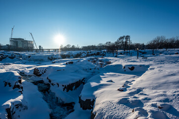 Sioux Falls Park during winter with frozen waterfall and snow cover.