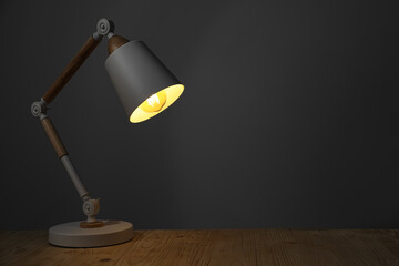 Stylish modern desk lamp on wooden table at night, space for text