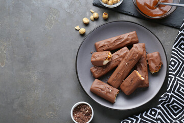 Tasty chocolate bars with caramel and nuts on grey table, flat lay. Space for text