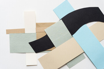 overlapping beige, green, blue, and black paper shapes on blank paper