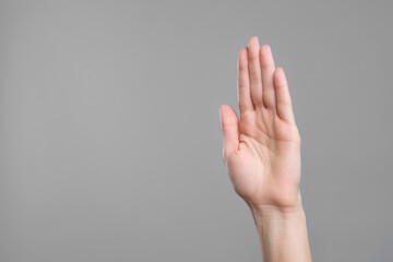 Woman giving high five on grey background, closeup. Space for text