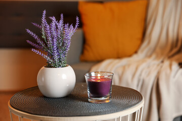 Burning candle and vase with lavender flowers on table indoors. Cosy atmosphere