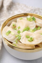 Cooked dumplings (varenyky) with tasty filling and green onion on light table, closeup