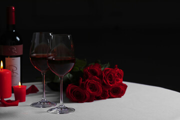 Fototapeta Romantic table setting with glasses of red wine, rose flowers and burning candles, space for text obraz