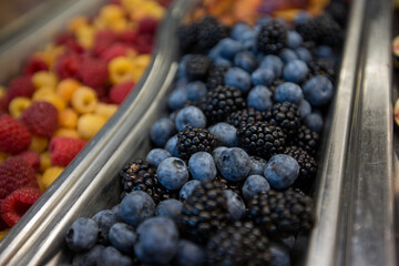 Close-up of fresh mixed blueberries and blackberries, in a silver container, at a fruit and salad buffet bar