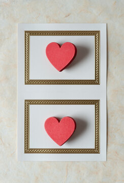 two wooden heart painted red on invitation cards isolated on textured paper