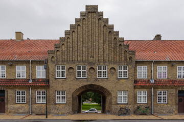 Fototapeta premium Exterior front elevation street view of typical old brick apartment with arch passage connect a road behind in Copenhagen, Denmark. 