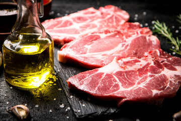 Raw pork steak on a stone board with tomato sauce, rosemary and spices. 