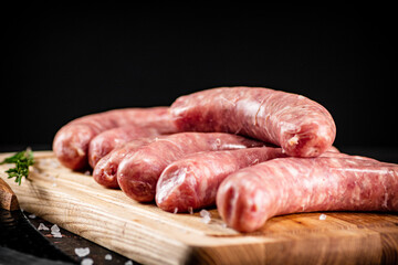Raw sausages on a wooden cutting board. 