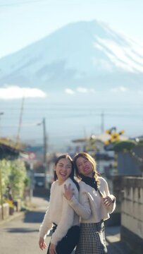 Asian woman friends walking and playing together on the street during travel in small town near mt Fuji in japan in autumn. Attractive girl enjoy outdoor lifestyle and local travel on holiday vacation