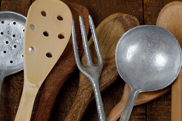 Wooden cutlery and cast aluminum cutlery on rustic wooden table. Traditional kitchen utensil in...